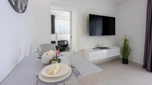 Habitació d'hotel moderna i minimalista amb zona de menjador, televisió de pantalla plana i una planta en test.