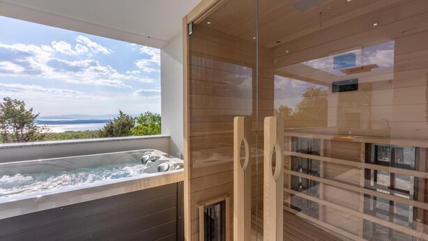 Un bany modern amb dutxa envidriada, banyera d'hidromassatge i vista a l'oceà.