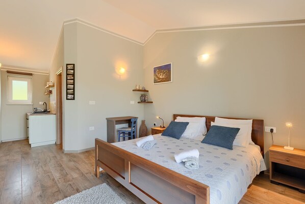 A bedroom with a wooden bed, bedside tables, a desk, and a chair. There is a window and a door leading to a bathroom. - Fantastic finca with table tennis, playground, basketball court, private pool, outdoor kitchen (Pazin)