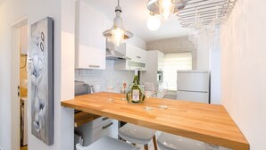 Una cocina moderna con isla de madera, armarios blancos e iluminación colgante.