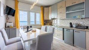 Una cocina moderna con comedor, ventanas amplias y vista al mar.