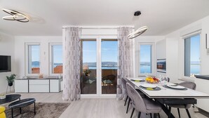 A modern kitchen with a dining area, large windows, and a view of the sea. - Light-flooded flat with sea view, private balcony, WiFi, private car park (Crikvenica)
