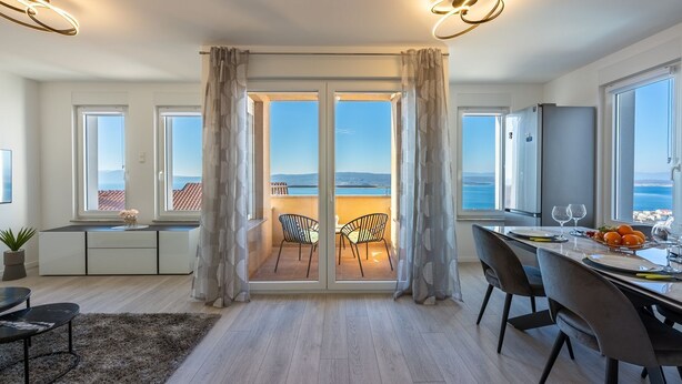 A modern kitchen with a dining area, large windows, and a view of the sea. - Light-flooded flat with sea view, private balcony, WiFi, private car park (Crikvenica)