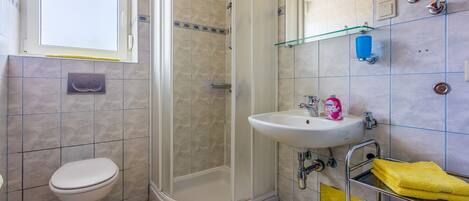 Un baño con inodoro, ducha, lavamanos y cabina de ducha de vidrio.