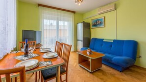 Un coin repas avec une table en bois dressée pour quatre personnes, un canapé bleu et un téléviseur.