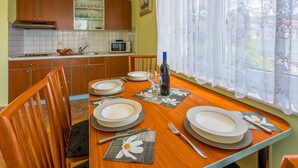 Un coin repas avec une table en bois mise pour quatre personnes, comprenant des assiettes, des couverts et une bouteille de vin.