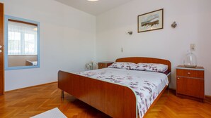 Une chambre à coucher avec un lit en bois, une table de chevet, une commode, une fenêtre donnant sur un beau paysage et un tableau encadré accroché au mur.