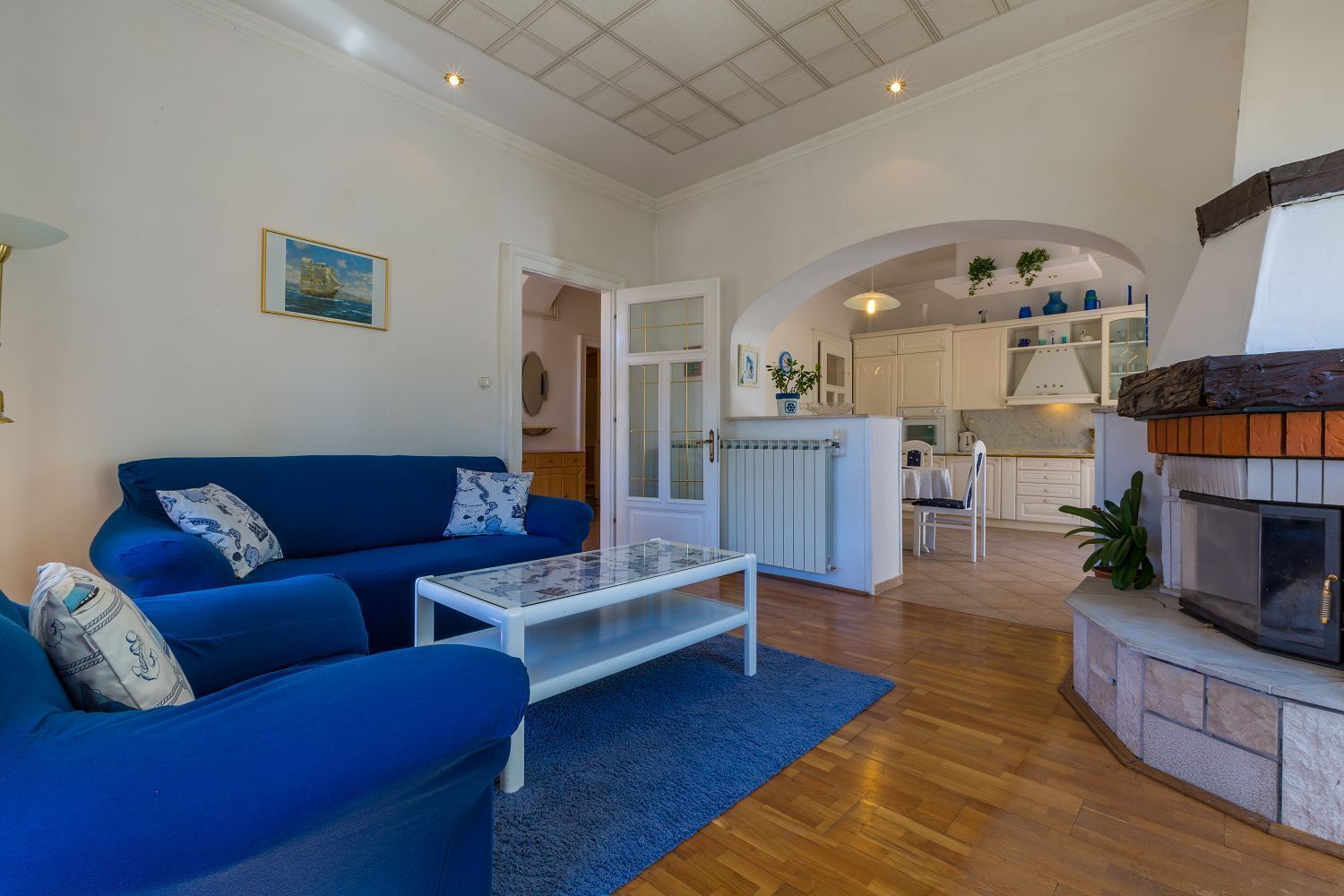 Una sala de estar con un sofá azul, una mesa de centro de vidrio y una chimenea.