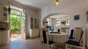 A dining area with a round table and four chairs, a television, and a cabinet with glass doors.