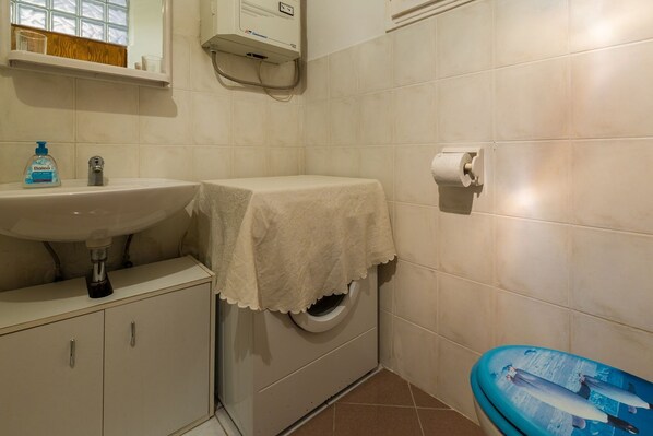 Un baño con lavamanos, inodoro y una bañera azul con diseño de delfín.