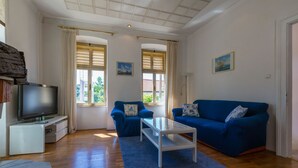 A living room with a TV, two sofas, a coffee table, and a window with curtains.