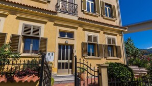 A yellow building with a balcony, a door, and a gate.