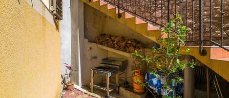 A small outdoor area with a metal staircase, a grill, and a potted plant.