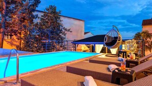 A swimming pool with lounge chairs and a hanging chair, surrounded by trees and buildings. - Stunning flat 150 metres to the beach with jacuzzi, sea view, pool, pool table (Dramalj)