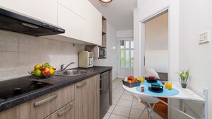 A modern kitchen with a sink, stove, and microwave. There is a dining area with a table set for breakfast, including croissants, coffee, and orange juice. - Stunning flat 150 metres to the beach with jacuzzi, sea view, pool, pool table (Dramalj)
