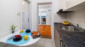 A compact kitchen with a dining area, a view to the outside, and a sink with fruits. - Stunning flat 150 metres to the beach with jacuzzi, sea view, pool, pool table (Dramalj)