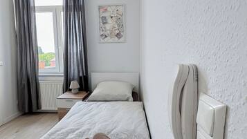 Une chambre d’hôtel avec un lit, une table de chevet avec une lampe, un téléphone et une fenêtre avec des rideaux.