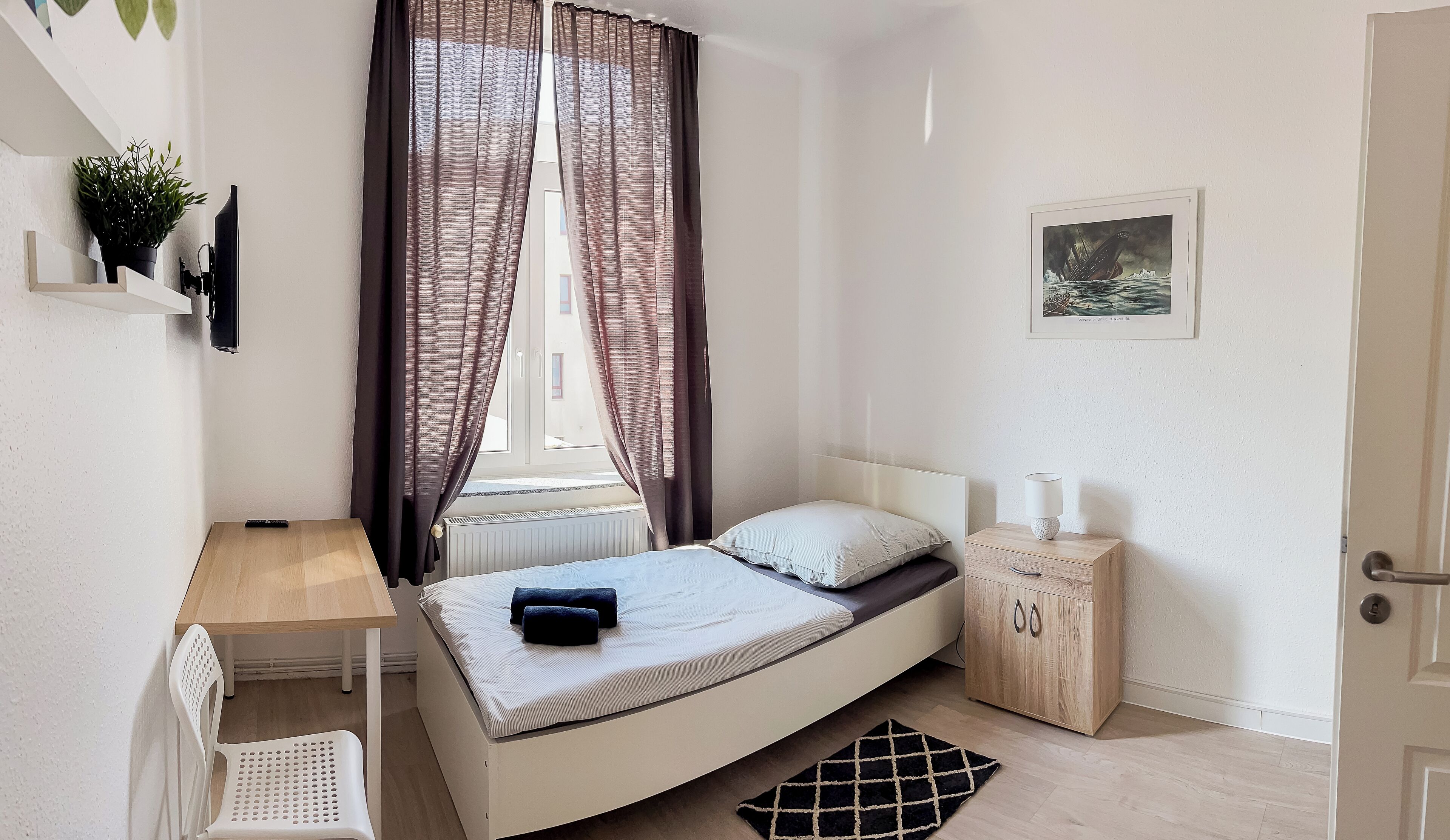 Ein Schlafzimmer mit einem Bett, einem Nachttisch, einer Lampe und einem kleinen Schrank.