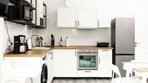 A modern kitchen with white cabinets, a stainless steel refrigerator, a built-in oven, and a coffee maker. - Apart Brunnen Bremerhaven (Bremerhaven)