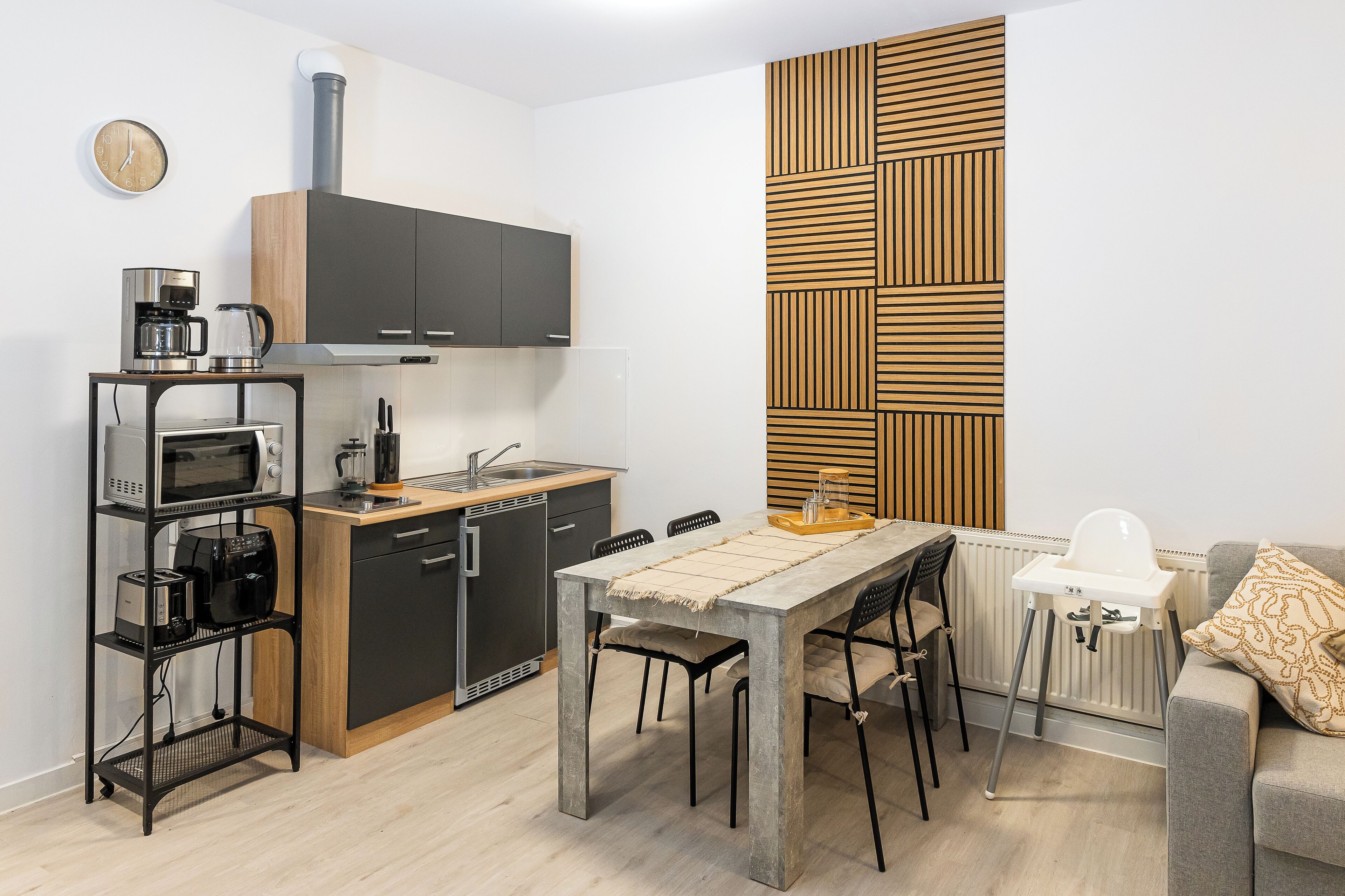 A compact kitchen with modern appliances, a dining table, and a high chair.