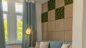 A modern living room with a blue sofa, a wooden coffee table, and a patterned wall. - Apart Brunnen Bremerhaven (Bremerhaven)