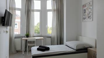 Een slaapkamer met een bed, een bureau en een stoel.