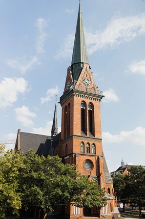 A tall brick church with a spire and clock tower. - Apart Brunnen Bremerhaven (Bremerhaven)