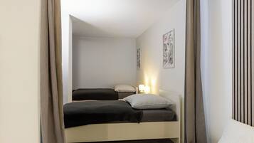 A bedroom with two beds, a bedside table with a lamp, and a wall-mounted artwork.