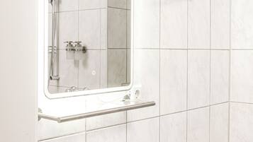 A modern bathroom with a white sink, a mirror, and a shower area.
