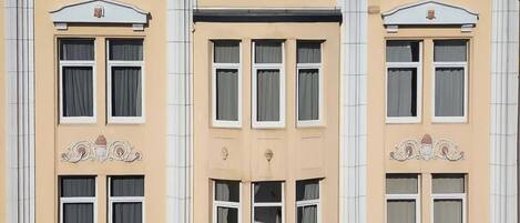 A multi-story building with a beige facade, symmetrical windows, and decorative elements.