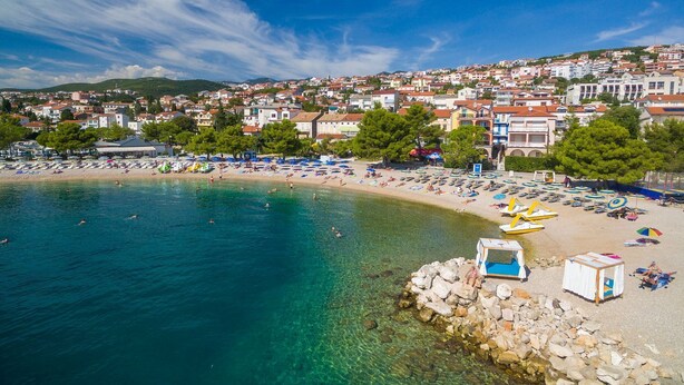 A coastal town with a beach, clear blue water, and buildings in the background. - Idyllic flat just 250 metres from the beach with sea views, private terrace, private parking space (Crikvenica)