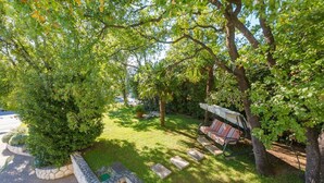 A garden with a stone bench and a swing. - Idyllic flat just 250 metres from the beach with sea views, private terrace, private parking space (Crikvenica)