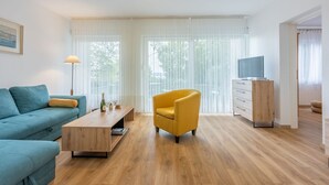 A modern living room with a sofa, a yellow armchair, a wooden coffee table, and a TV stand. - Idyllic flat just 250 metres from the beach with sea views, private terrace, private parking space (Crikvenica)