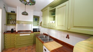 A kitchen with green cabinets, a wooden countertop, a stainless steel sink, and a hanging light fixture. - Masnou Chill - Penthouse Terrace in front of the Beach (El Masnou)