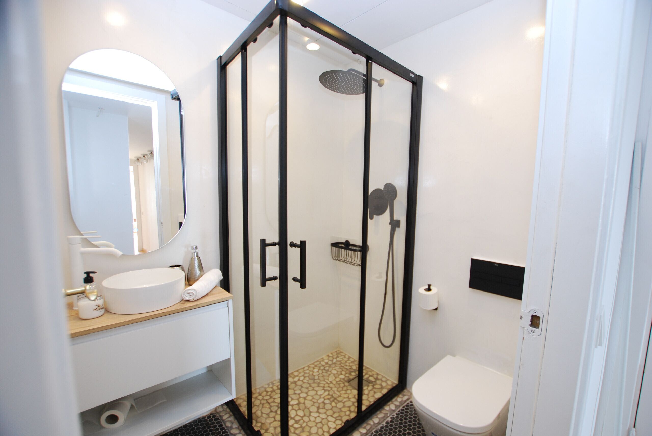 Une salle de bain moderne avec une douche à parois de verre, un lavabo blanc et des toilettes.