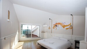 A bedroom with a large bed, a window with a view, a wall-mounted light fixture, and a hanging light. - Masnou Chill - Penthouse Terrace in front of the Beach (El Masnou)