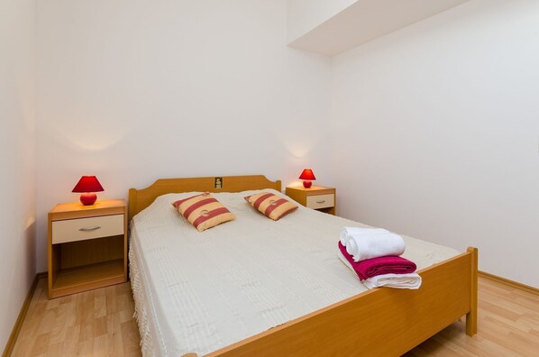 A single bed with a wooden frame, two bedside tables, and two red lamps.