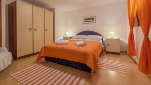 Une chambre à coucher avec un lit, deux tables de chevet, une armoire et un tableau au mur.