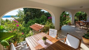 An outdoor patio with a wooden table and chairs, surrounded by potted plants and a view of the sea. - Fantastic flat with its own wine cellar, hydromassage shower, sea view - only 480 metres to the beach (Crikvenica)