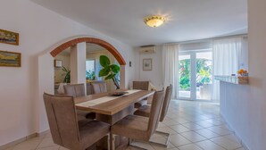 A dining area with a long wooden table, cushioned chairs, and a large plant. - Fantastic flat with its own wine cellar, hydromassage shower, sea view - only 480 metres to the beach (Crikvenica)