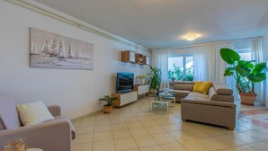 A living room with a sofa, a coffee table, a TV, and a painting on the wall. - Fantastic flat with its own wine cellar, hydromassage shower, sea view - only 480 metres to the beach (Crikvenica)