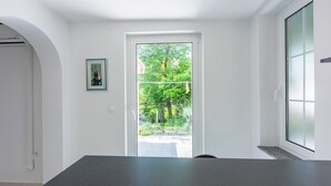 Habitación moderna y minimalista con un ventanal grande, una puerta que da a un área exterior y un cuadro enmarcado en la pared.