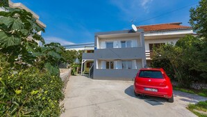 A two-story residential building with a red car parked in front. - Mediterranean flat with three terraces, barbecue, WiFi - only 500 metres to the beach (Crikvenica)