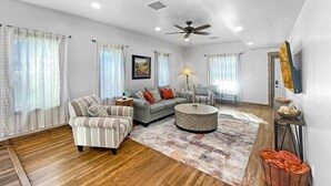 A spacious living room with a sofa, armchair, and round coffee table. - Colorado Willow House (Cortez)