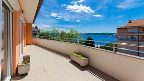 A balcony with a view of a lake and distant hills, a tiled floor, and a potted plant. - Idyllic flat just 400 metres from the sandy beach with sea views, WiFi and private parking (Crikvenica)