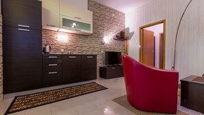 A modern kitchen with dark cabinets, a stone backsplash, and a red chair.