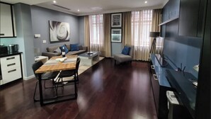 A modern living room with a dining area, a sofa, a coffee table, and a TV mounted on the wall. - Chic and Renovated 1bd/1bth (Cape Town)