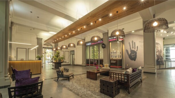 A spacious lobby with a high ceiling, wooden beams, and modern lighting fixtures. There are seating areas with cushions and a reception desk. - Chic and Renovated 1bd/1bth (Cape Town)