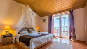 A bedroom with a canopy bed, two bedside lamps, a large window with curtains, and a balcony view. - Charming flat just 700 metres from the beach with sea views, pool, BBQ, private parking (Crikvenica)