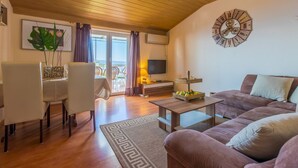 A cozy living room with a wooden ceiling, a sofa, a coffee table, and a TV. - Charming flat just 700 metres from the beach with sea views, pool, BBQ, private parking (Crikvenica)